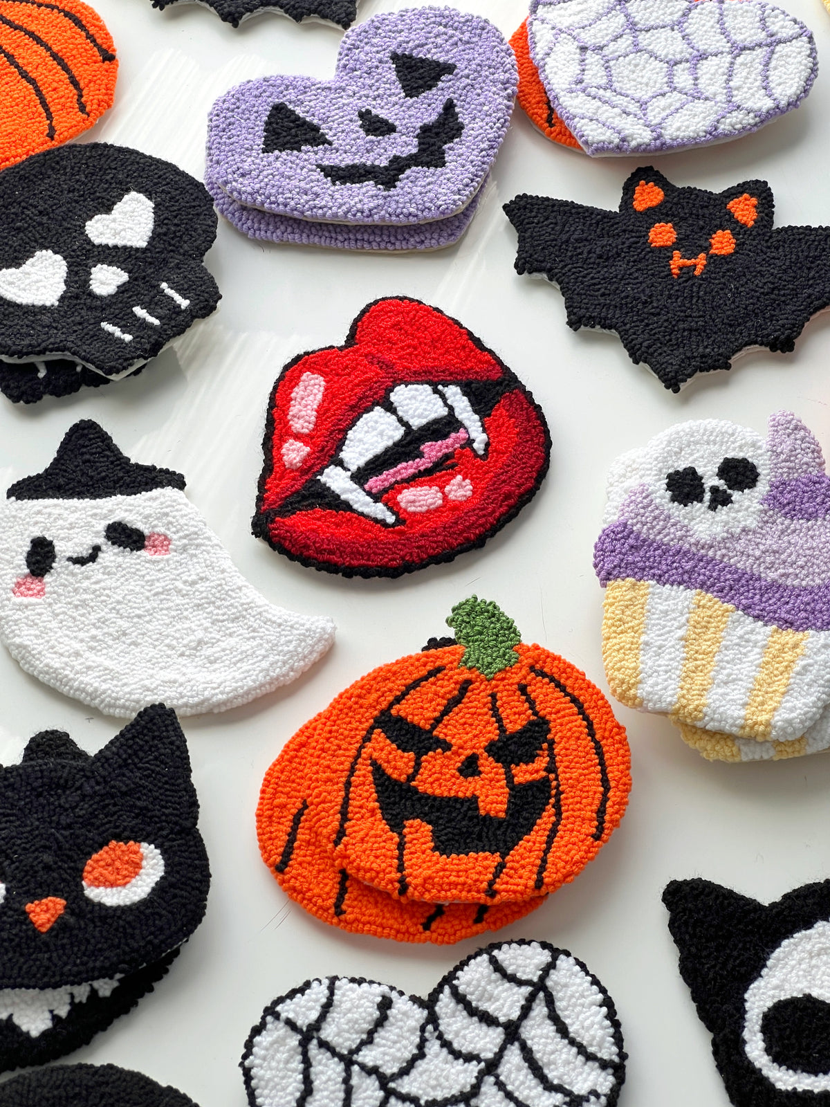 Flat lay of classic Halloween punch needle coasters with a jack-o-lantern, a ghost and a bat