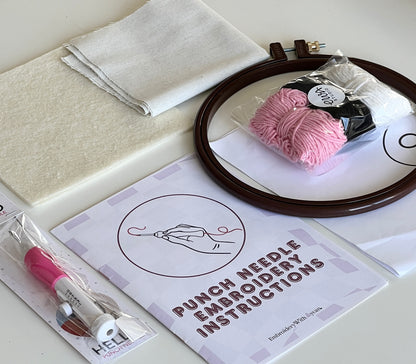 Punch needle kit contents laid out with fabric, hoop, yarn and instruction booklet