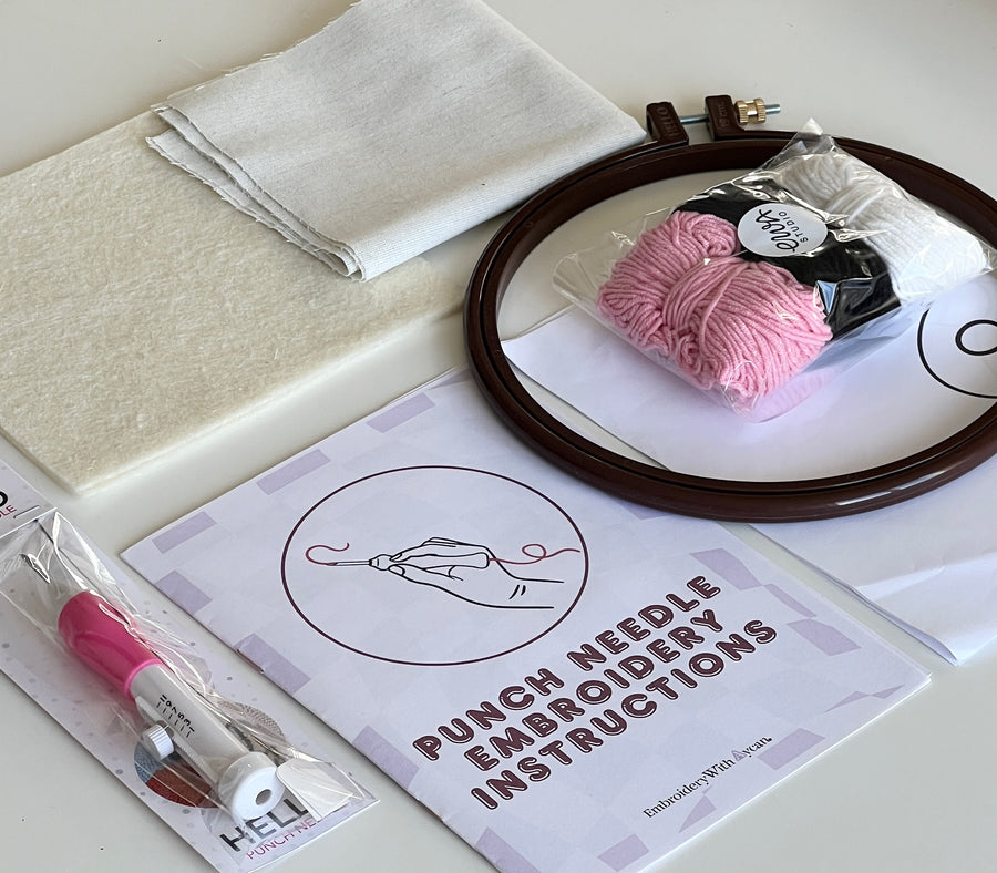 Punch needle kit contents laid out with fabric, hoop, yarn and instruction booklet