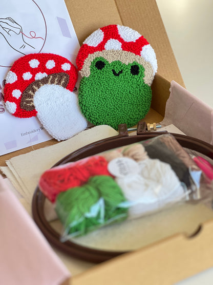 Punch needle kit box with frog and mushroom coasters, yarn, hoop and needle