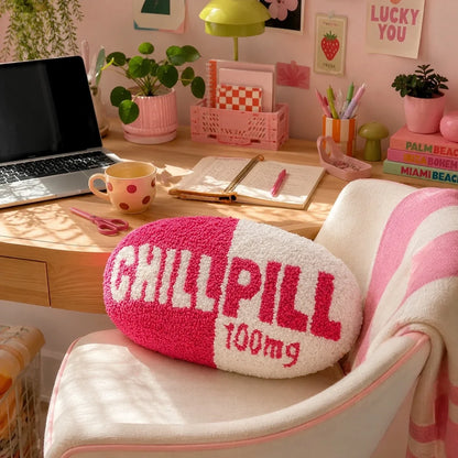 Chill Pill pillow on a chair at a pink desk with a laptop