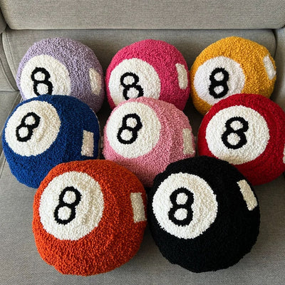 Magic 8 Ball punch needle pillows in nine colors styled on a couch