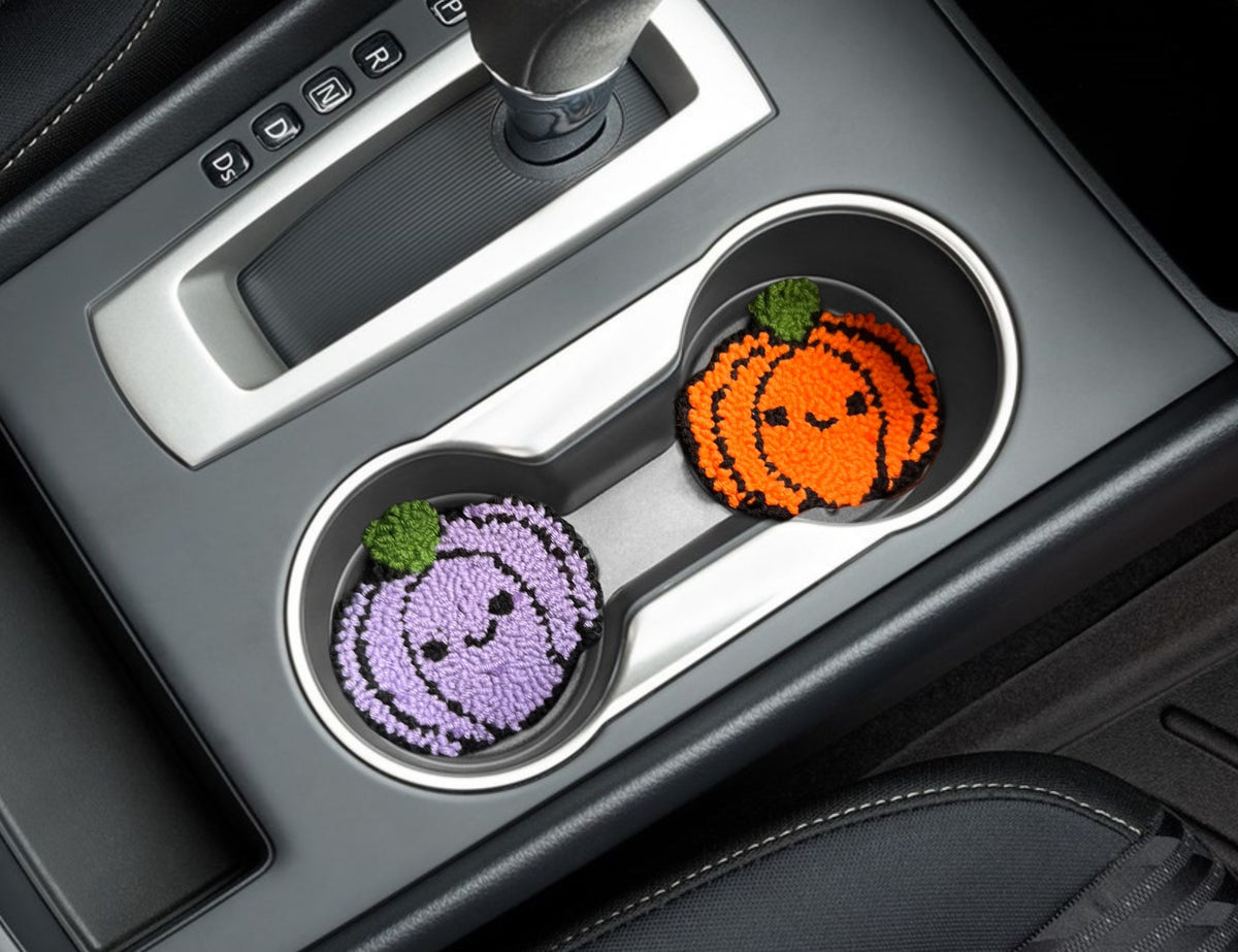 Purple and orange pumpkin car coasters in a car cup holder